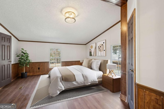 bedroom featuring crown molding, lofted ceiling, hardwood / wood-style floors, and a textured ceiling