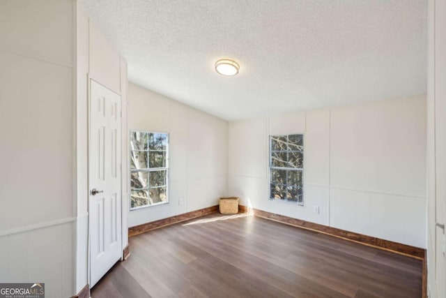 unfurnished room featuring vaulted ceiling, a textured ceiling, and dark hardwood / wood-style flooring