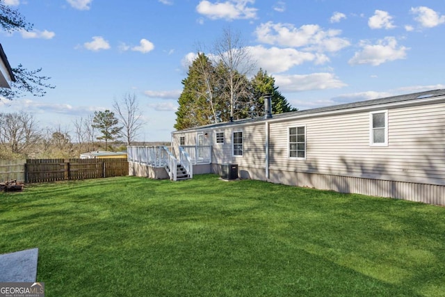 rear view of house featuring cooling unit, a yard, and a wooden deck