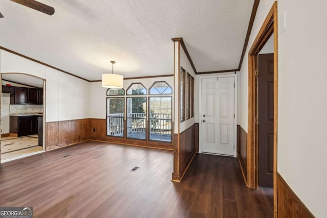 interior space featuring dark hardwood / wood-style flooring, crown molding, a textured ceiling, and wood walls