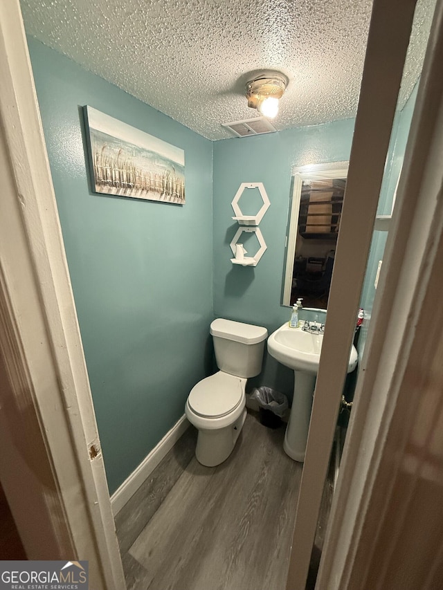 bathroom featuring sink, hardwood / wood-style floors, a textured ceiling, and toilet