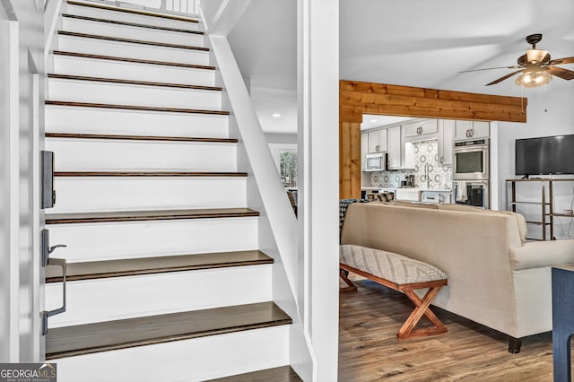 staircase featuring wood-type flooring and ceiling fan