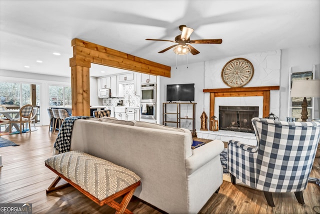 living room with ceiling fan, a fireplace, and light hardwood / wood-style flooring