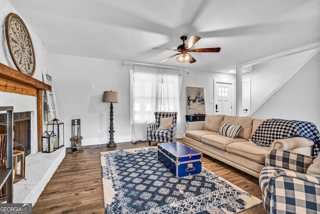 living room featuring wood-type flooring, ceiling fan, and a fireplace