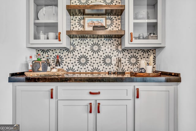 bar with white cabinetry, dark stone countertops, and backsplash