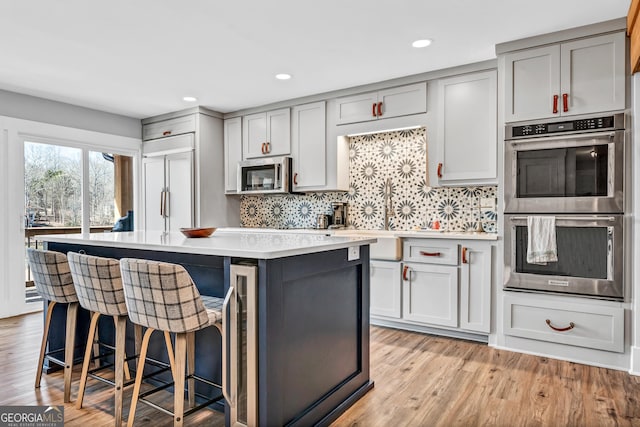 kitchen featuring a center island, appliances with stainless steel finishes, a breakfast bar, and gray cabinetry