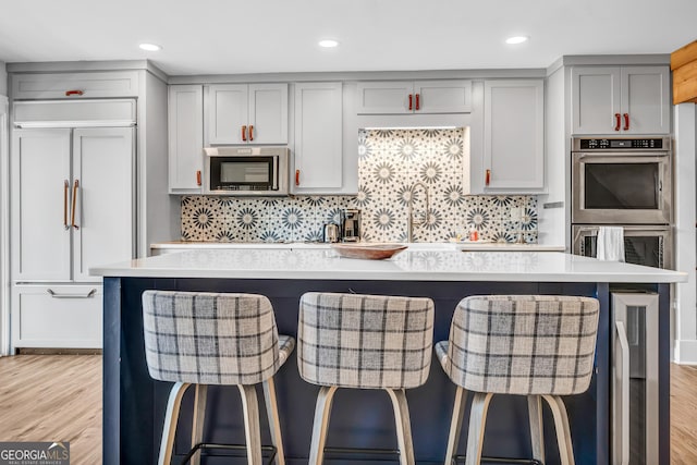 kitchen featuring a kitchen island, gray cabinets, a breakfast bar, and appliances with stainless steel finishes