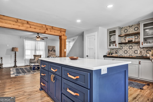 kitchen featuring a center island, blue cabinetry, light hardwood / wood-style floors, and decorative backsplash