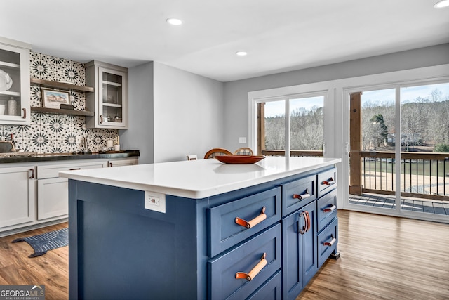 kitchen featuring blue cabinetry, tasteful backsplash, white cabinets, a kitchen island, and light wood-type flooring