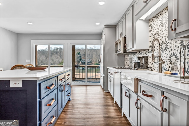 kitchen with backsplash, wood-type flooring, sink, and blue cabinets