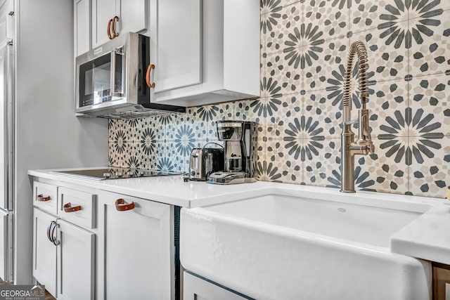 kitchen with tasteful backsplash, sink, white cabinetry, and black electric stovetop