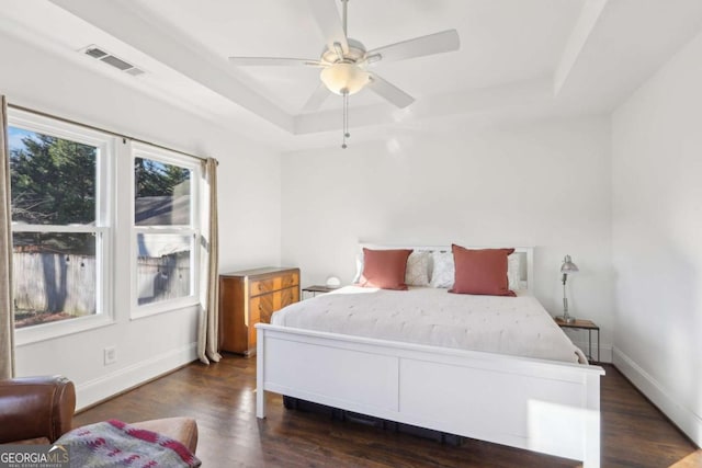 bedroom featuring dark hardwood / wood-style floors, a raised ceiling, and ceiling fan