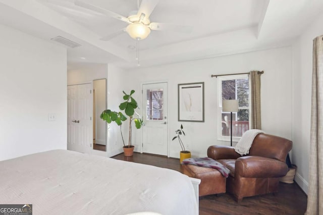 bedroom featuring ceiling fan, dark hardwood / wood-style flooring, and a tray ceiling