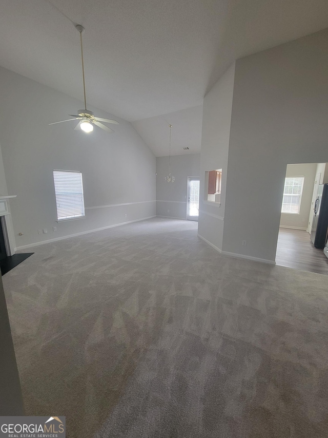 unfurnished living room with high vaulted ceiling, a healthy amount of sunlight, and carpet flooring