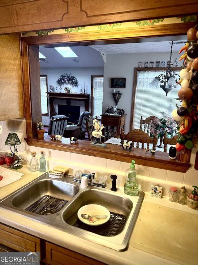 kitchen with tasteful backsplash, sink, and an inviting chandelier