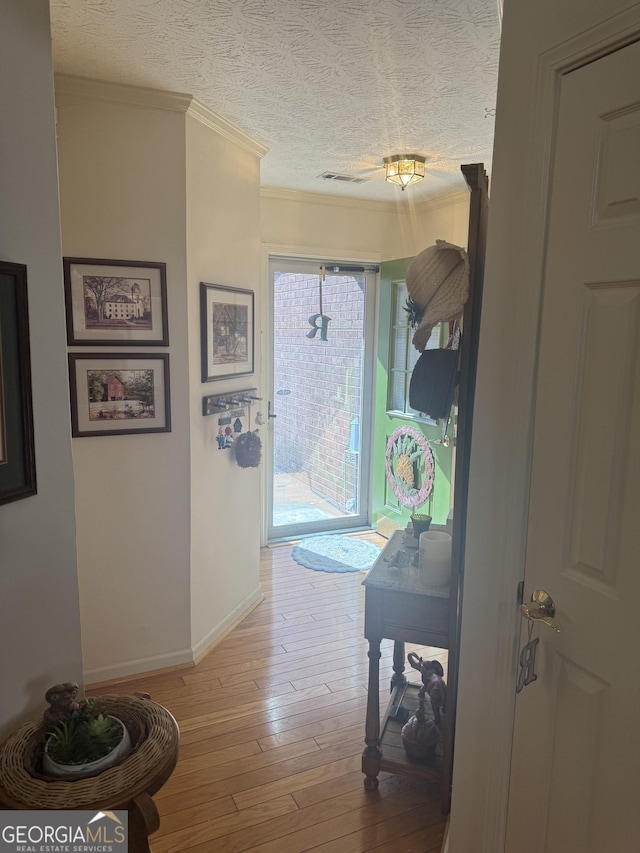 hallway with crown molding, hardwood / wood-style flooring, and a textured ceiling