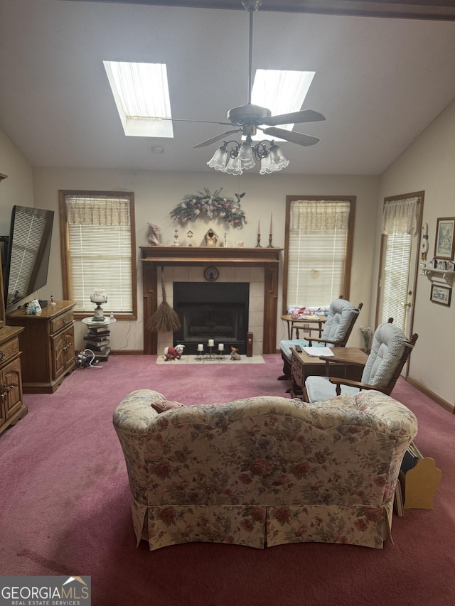 carpeted living room with lofted ceiling with skylight, ceiling fan, and a fireplace