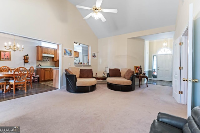 living room with ceiling fan with notable chandelier, high vaulted ceiling, and dark colored carpet