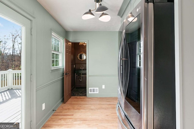 interior space with pendant lighting, stainless steel refrigerator, and light wood-type flooring