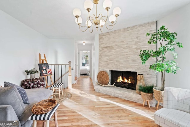 living room featuring an inviting chandelier, hardwood / wood-style floors, and a stone fireplace