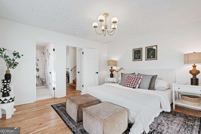 bedroom with ensuite bathroom, a notable chandelier, and light hardwood / wood-style flooring