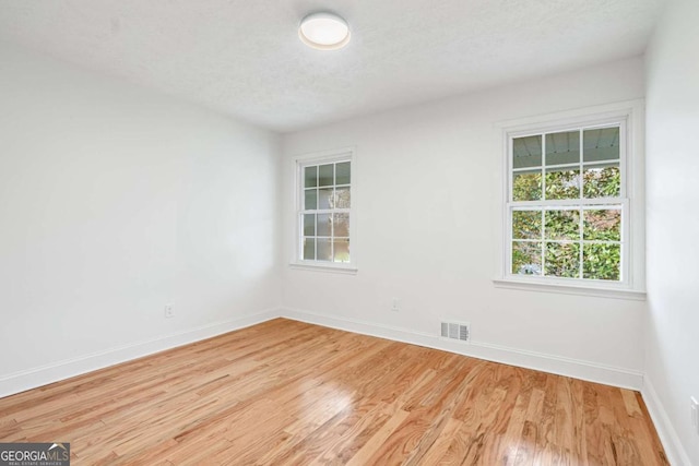 empty room with a textured ceiling and light wood-type flooring