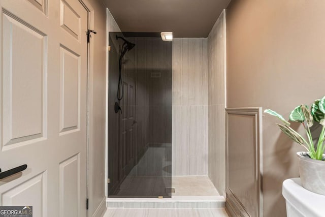 bathroom featuring a shower with shower door and toilet