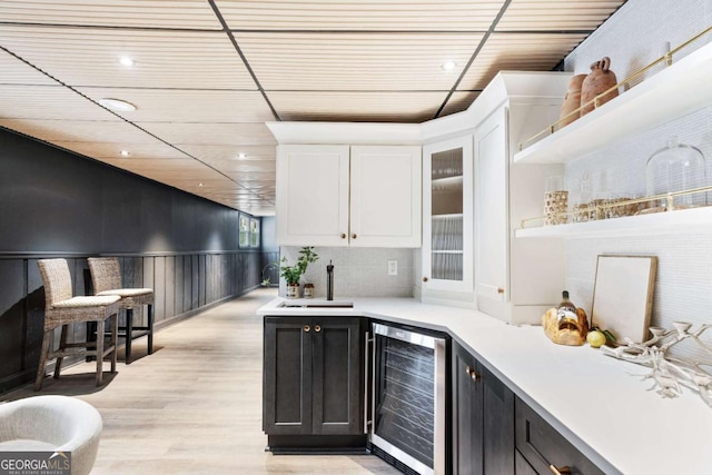 kitchen with white cabinetry, sink, beverage cooler, and light hardwood / wood-style floors