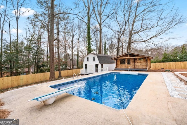 view of pool with an outdoor structure, a diving board, and a patio area