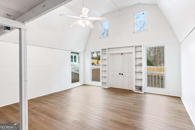 unfurnished living room with wood-type flooring, high vaulted ceiling, and ceiling fan