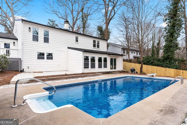 view of swimming pool featuring a diving board and a patio