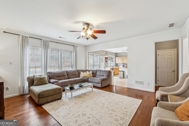 living room featuring dark wood-type flooring and ceiling fan