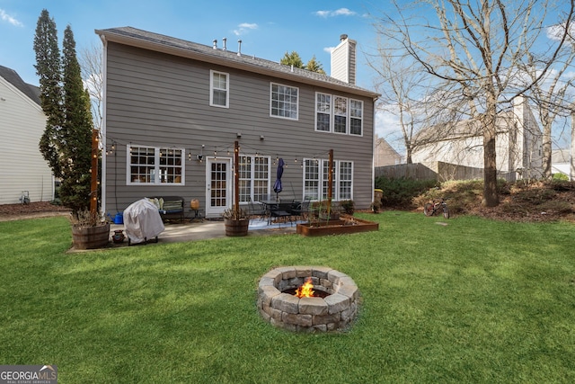 back of property featuring a fire pit, a lawn, and a patio