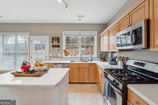 kitchen featuring a healthy amount of sunlight, stainless steel appliances, sink, and light tile patterned floors