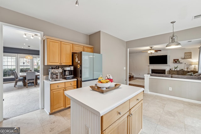 kitchen with light brown cabinetry, a center island, refrigerator, light colored carpet, and ceiling fan