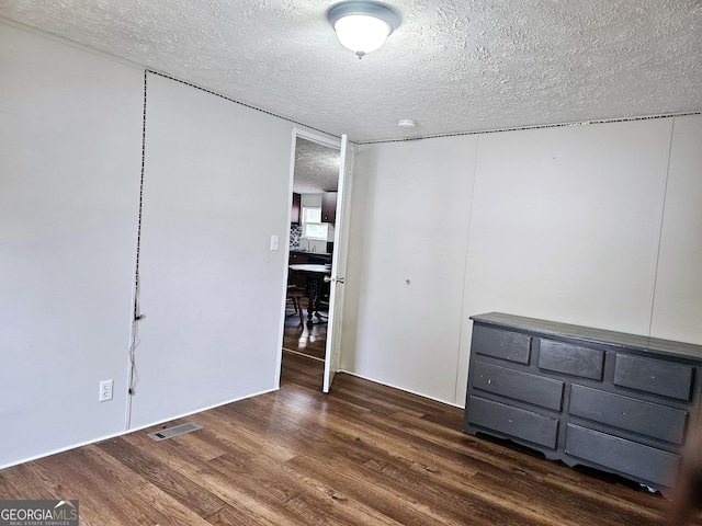 unfurnished bedroom featuring dark hardwood / wood-style floors and a textured ceiling