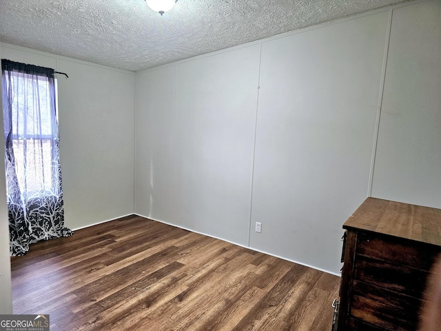 unfurnished room featuring dark wood-type flooring and a textured ceiling