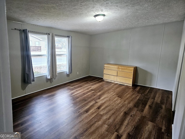 unfurnished room featuring dark hardwood / wood-style flooring and a textured ceiling