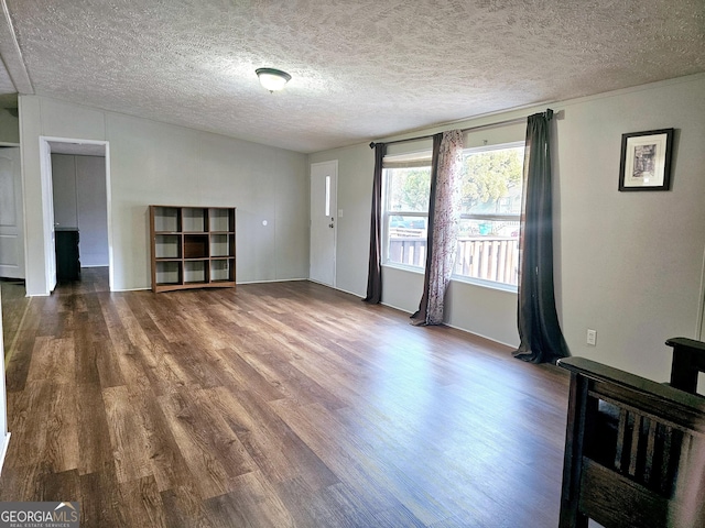 unfurnished living room with dark wood-type flooring and a textured ceiling