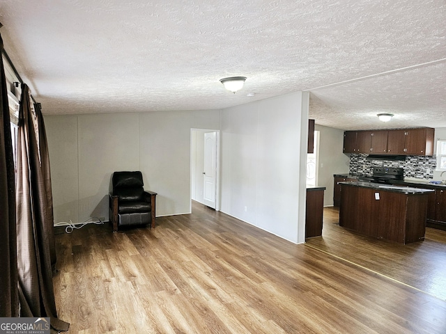 kitchen with dark brown cabinetry, backsplash, light hardwood / wood-style flooring, and black range with electric cooktop