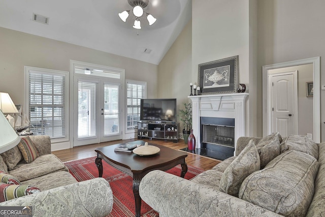 living room featuring wood-type flooring, high vaulted ceiling, ceiling fan, and french doors