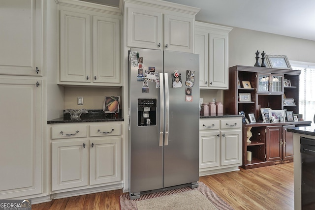 kitchen with dark stone countertops, light wood-type flooring, and stainless steel refrigerator with ice dispenser