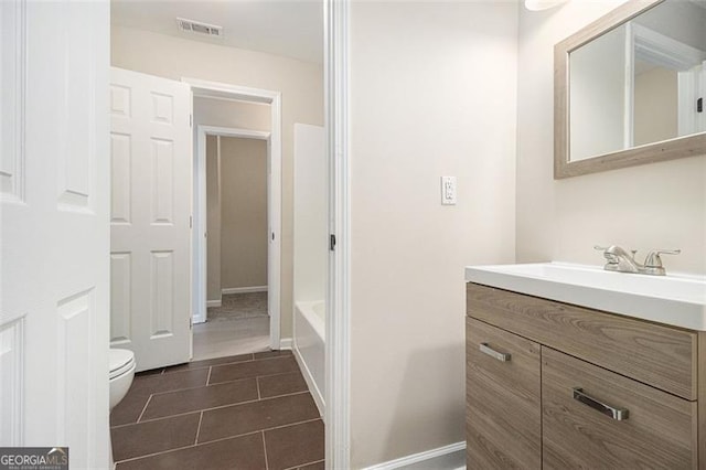 bathroom with tile patterned flooring, vanity, a bathtub, and toilet