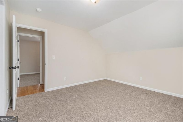 carpeted spare room with vaulted ceiling