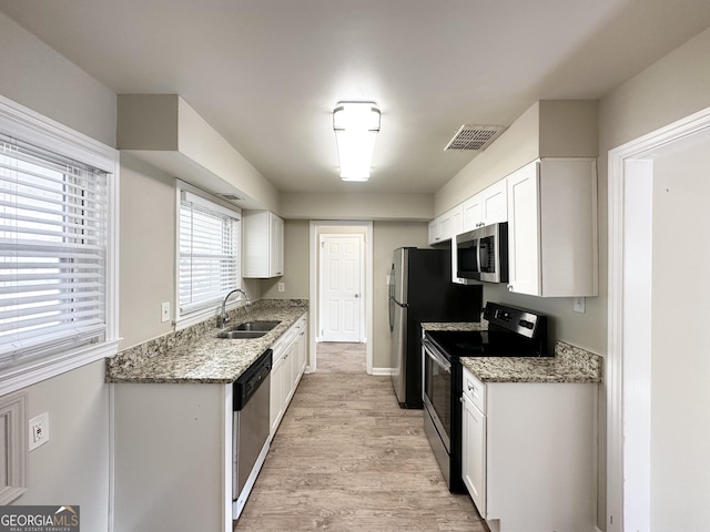 kitchen featuring stone counters, appliances with stainless steel finishes, sink, and white cabinets