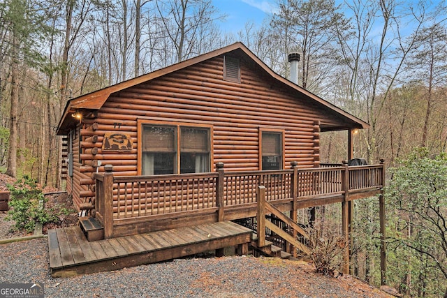 rear view of house featuring log exterior and a wooden deck