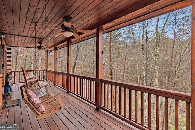 wooden deck with ceiling fan and a forest view