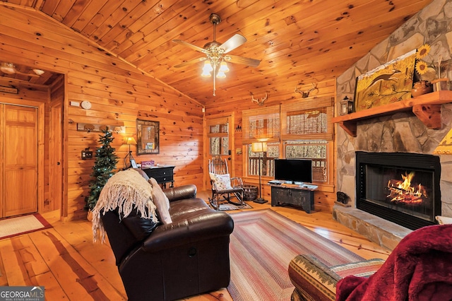 living area with light wood-style floors, vaulted ceiling, and a stone fireplace