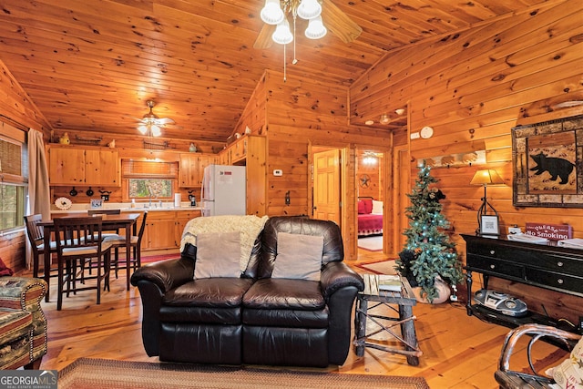 living room featuring lofted ceiling, wooden ceiling, ceiling fan, light wood-style flooring, and wood walls