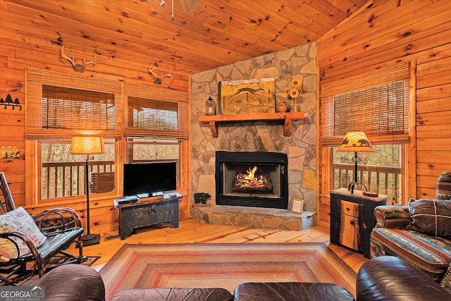 living area with high vaulted ceiling, a stone fireplace, wooden ceiling, wooden walls, and wood finished floors